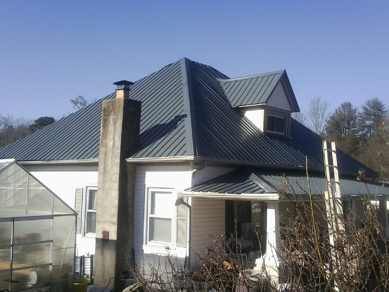 Dark blue standing seam metal roof on a white farmhouse with dormer — Slate & Tile Roof Repair by Roofing Brothers in Due West