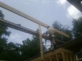 Carpenter setting a ridge beam over a new addition frame — Ice Dam Removal by Roofing Brothers in Due West