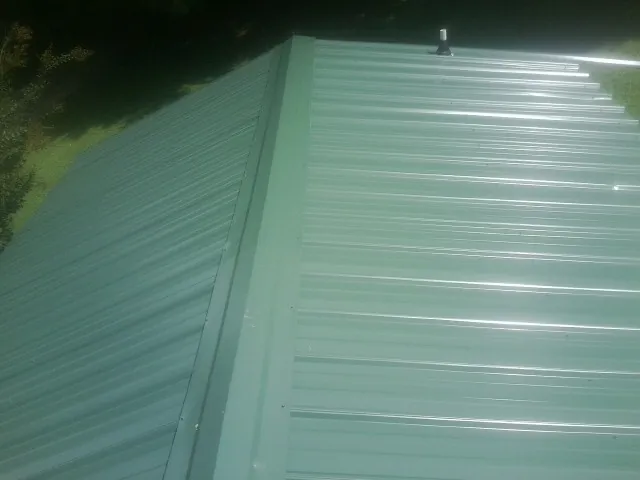 New green metal panels meeting at the ridge of a roof — Flat Roof Repair work by our crew in Due West