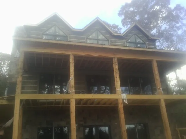 Dormers and porch framing on a large log home under construction — Roof Coating work by our crew in Due West