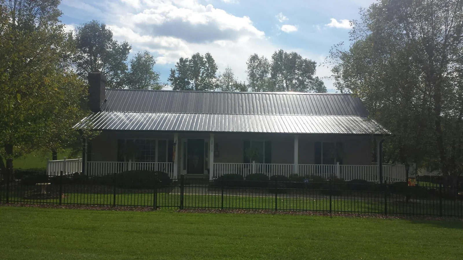 Gray metal roof on a brick ranch with a full width front porch — Gutter Guard Installation work by our crew in Due West