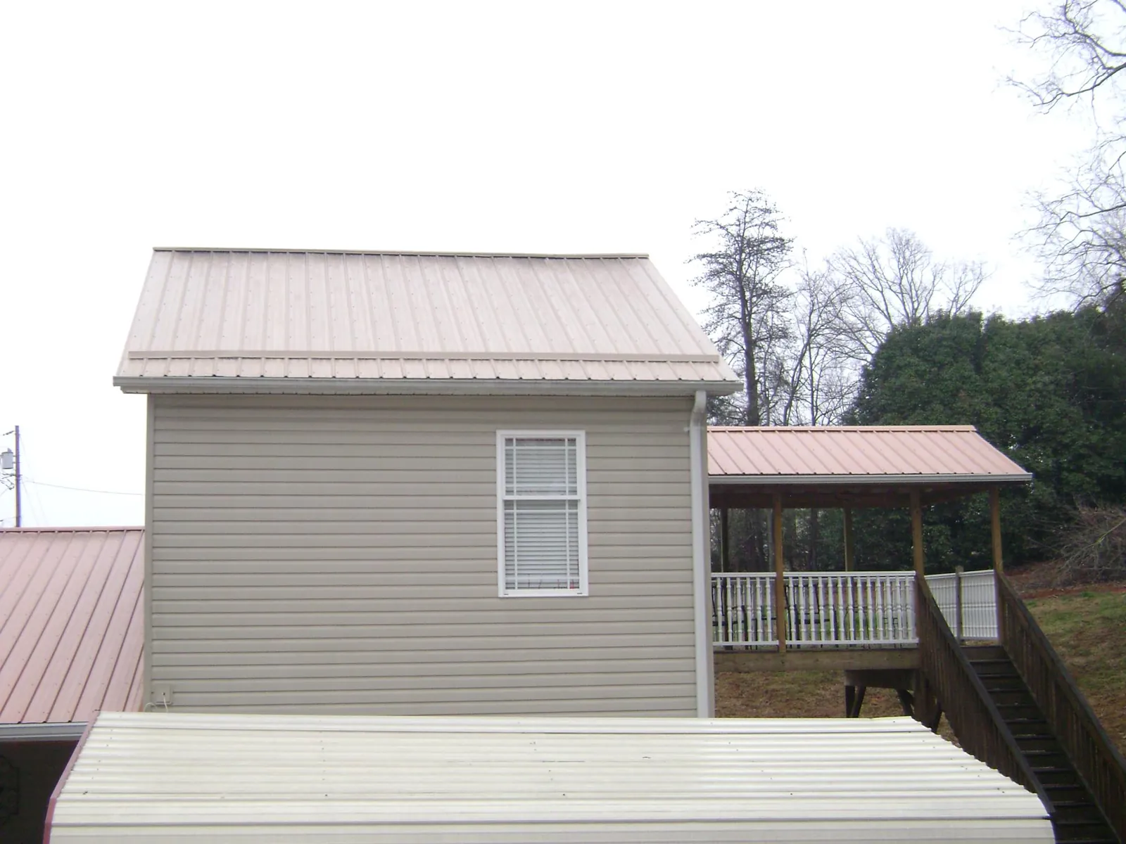 Tan metal roofs on a two story addition and attached porch, from a Roof Replacement job in Due West