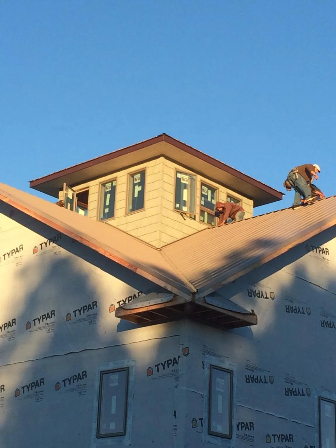 Roofers working around a rooftop cupola on a new metal roof at sunset — Roof Waterproofing in Due West by Roofing Brothers